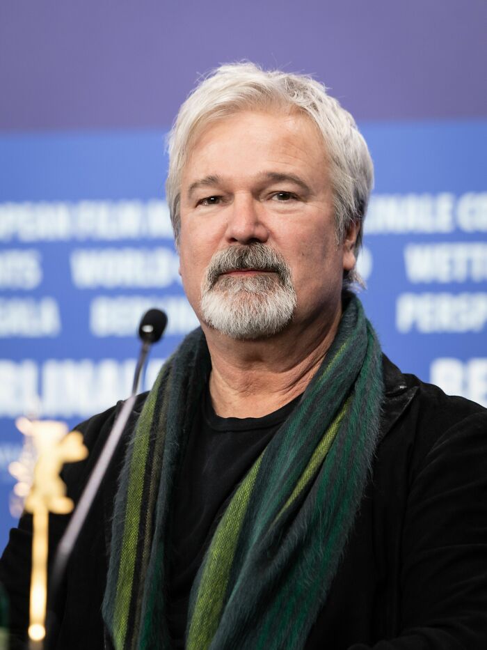 Gore Verbinski at a film event, wearing a green scarf and black jacket, speaking on his bio and career highlights.