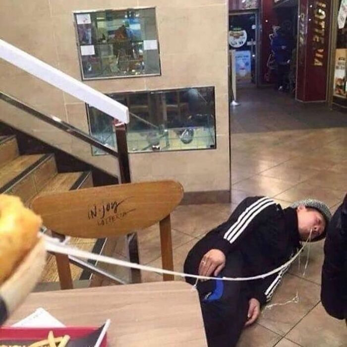 Person lying on the floor with unusual earphone positioning in a restaurant, showcasing a weird and cringey photo moment.
