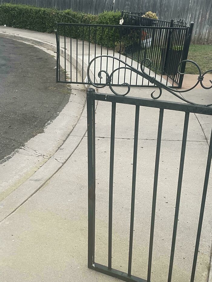 Iron gate attached to another gate and a fence on a suburban sidewalk, illustrating unusual neighbors causing frustration.