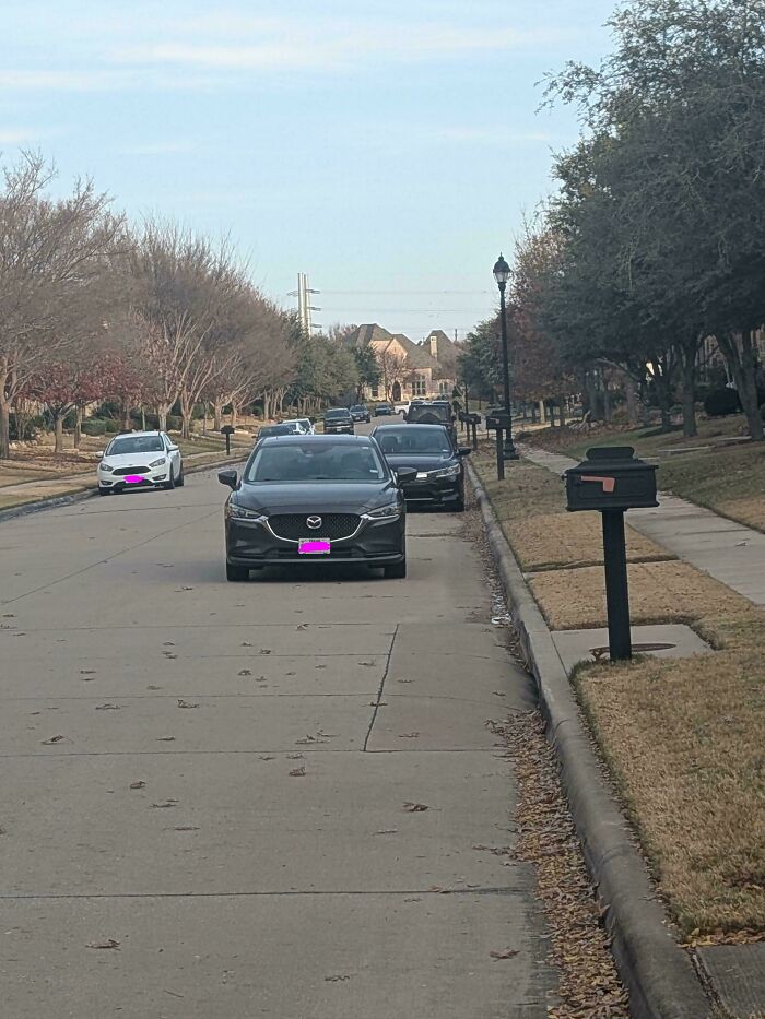 Suburban street with cars parked closely side by side, illustrating neighbors that would make you move to nowhere.
