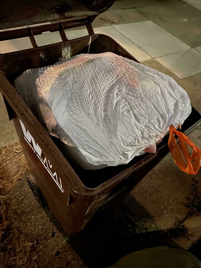 A large turkey wrapped in plastic inside a trash bin, illustrating one of the neighbors that would make you move far away.