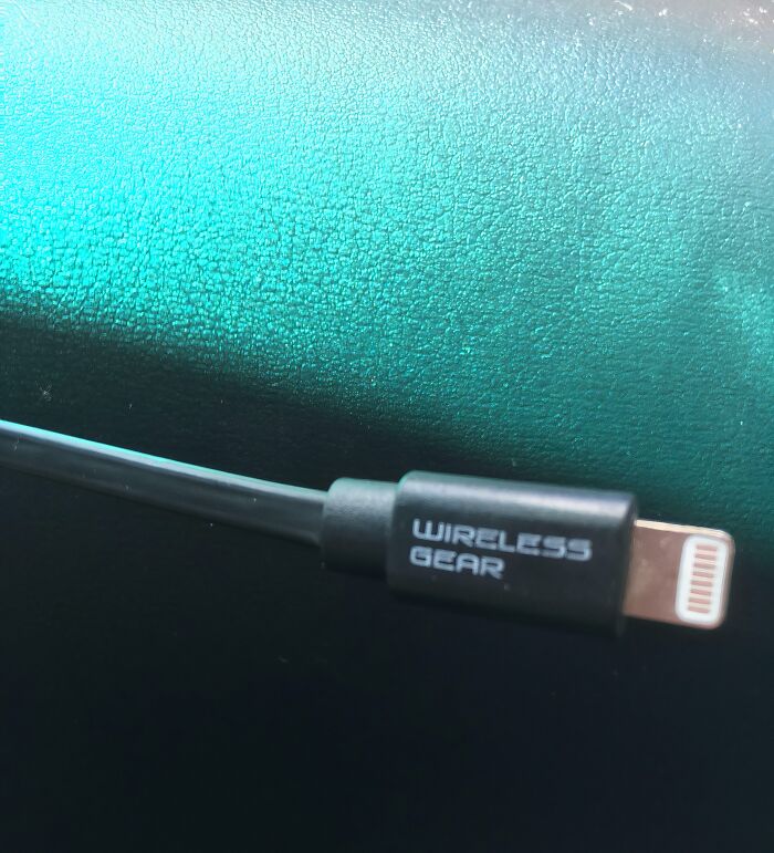 Close-up of a wired charging cable labeled wireless gear on a textured blue and black surface in a sarcastic image.