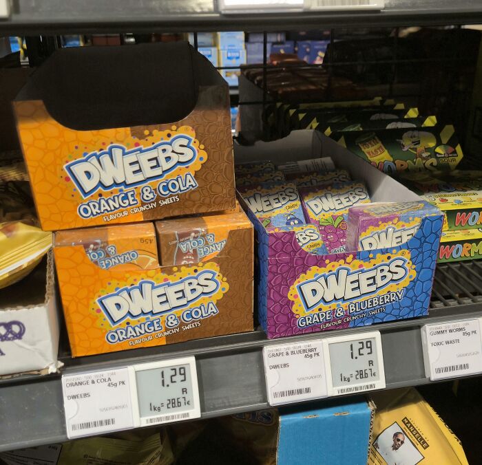Dweebs candy packaging mimics famous brand styles with orange & cola and grape & blueberry flavors on store shelf.