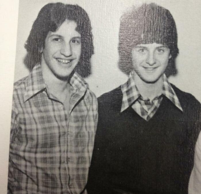 Two young men in old photographs wearing 70s fashion with plaid shirts and unique hairstyles suggesting time travel mystery.