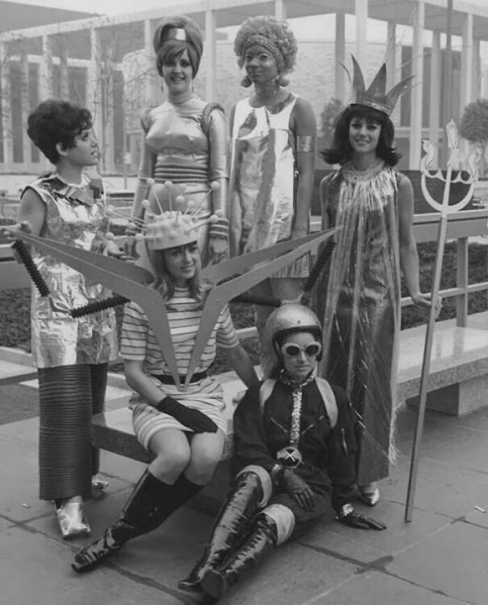 Group of people in bizarre vintage sci-fi costumes posing outdoors in a throwback moment from the past.