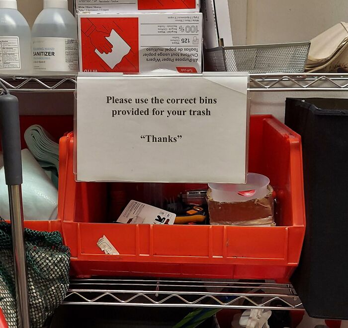 A sign with suspicious quotation marks around “Thanks” placed above red bins in a storage area.