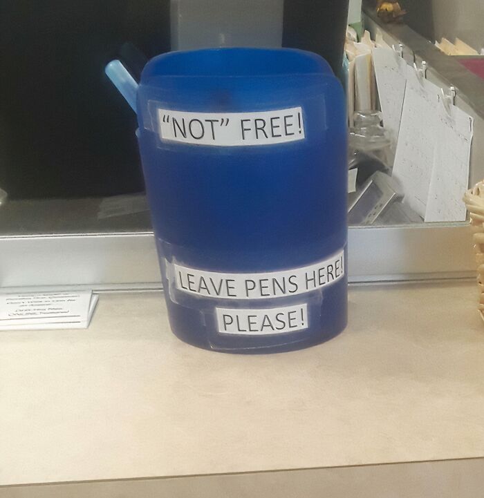 Blue container with a sign that uses suspicious quotation marks around "NOT" and requests to leave pens here.