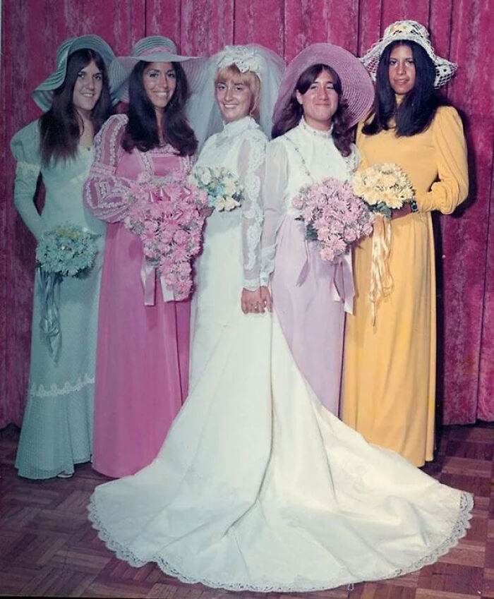 A group of women in colorful dresses, including a bride, in a candid old photo from generations ago.