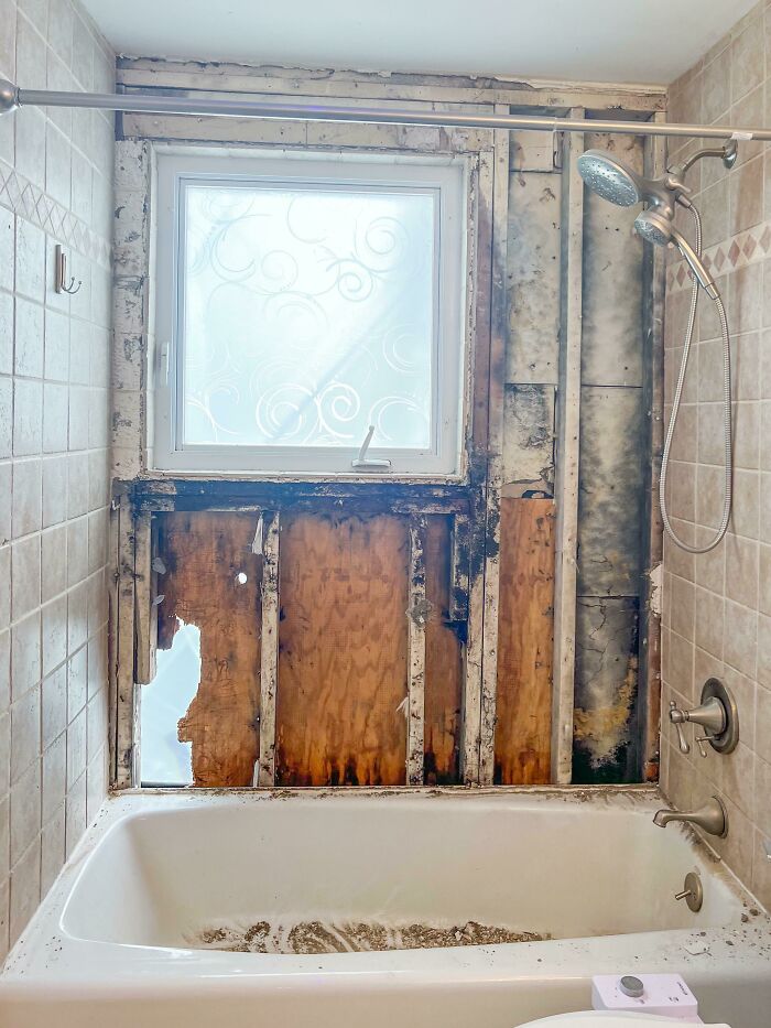 Bathroom with mold damage and exposed wood behind tub showing common issues in homes people bought and regretted.