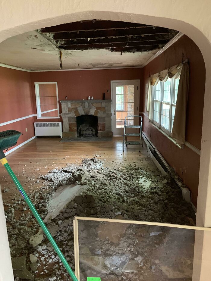 Living room in a home with severe ceiling damage and debris on the floor, showing a common regret in buying homes.