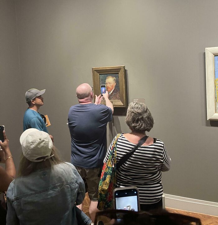 Tourists taking photos of museum art, showing rude and entitled behavior while visiting an exhibit.