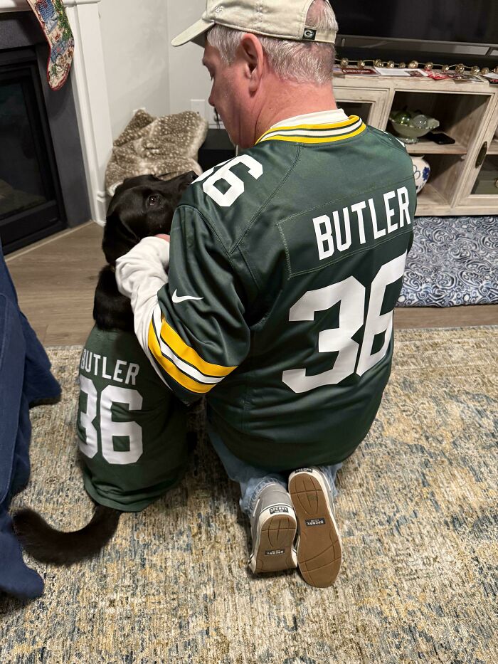 Dad and his dog wearing matching sports jerseys, showing the bond between dads and pets they never wanted but love.