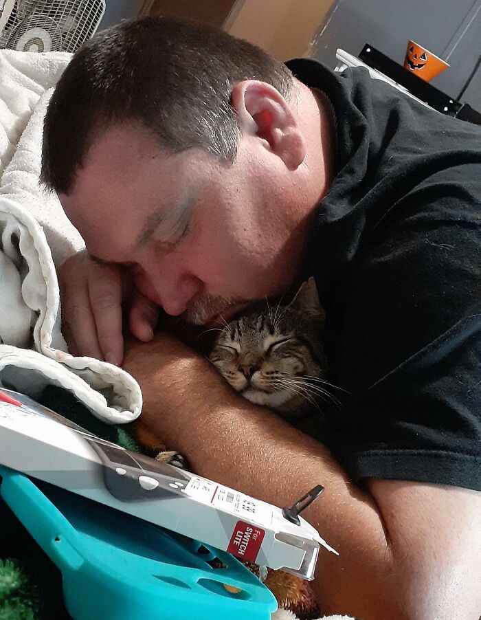Man cuddling a smiling cat, showing a dad and the pet he never wanted but now absolutely loves.