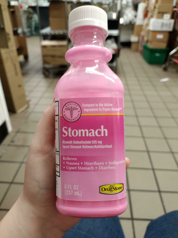 Hand holding a pink upset stomach reliever bottle mimicking famous brand packaging in a store setting.