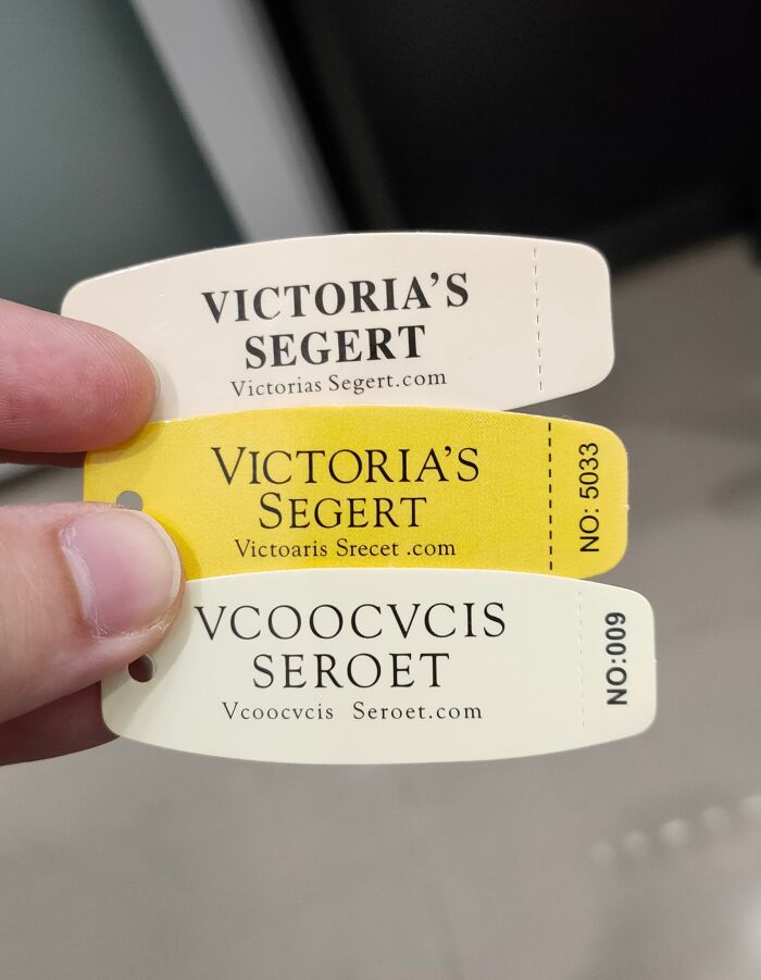 Hand holding three fake Victoria's Secret tags showing shameless designer attempts to copy famous brands.