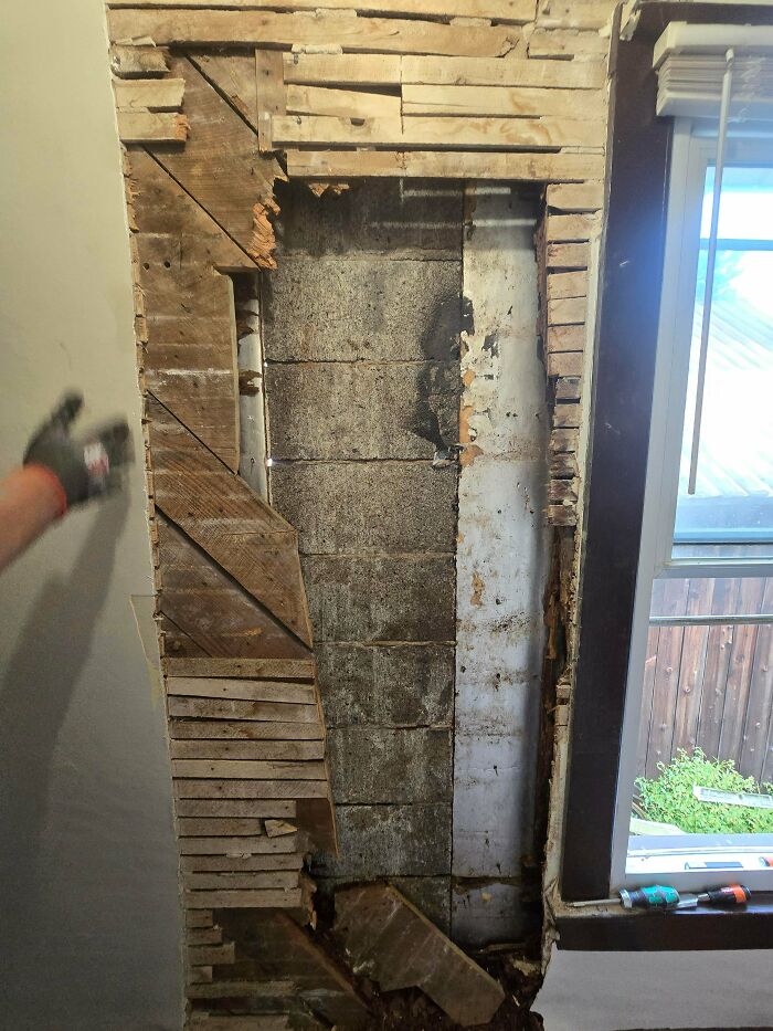 Exposed damaged wall revealing old lath and plaster with signs of decay in a home renovation scene.