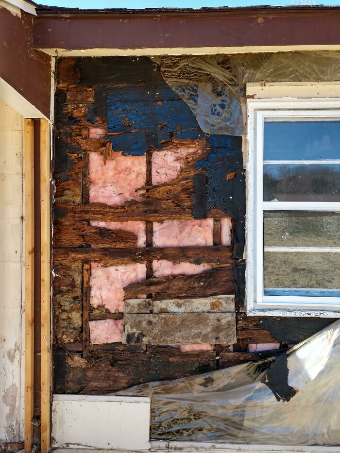 Severely damaged house exterior with rotting wood and exposed insulation showing home buying regrets.