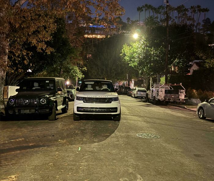 Nighttime street scene with parked cars and dim streetlights in a quiet neighborhood away from neighbors