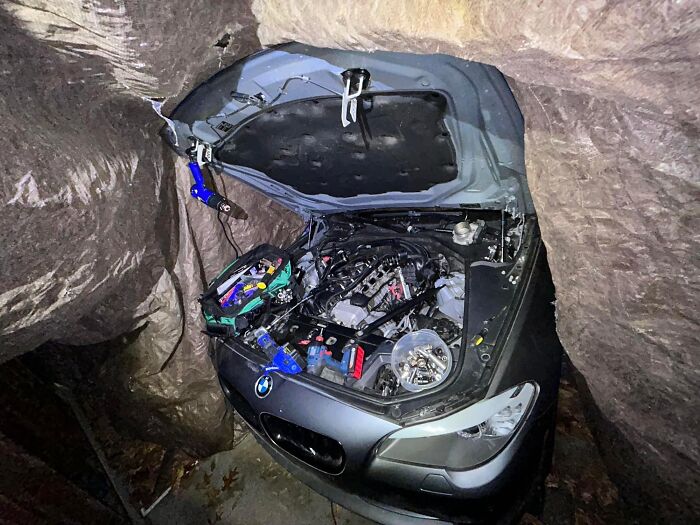 Car with open hood and complex engine inside a cave, one of the unedited photos that might mess with your brain.