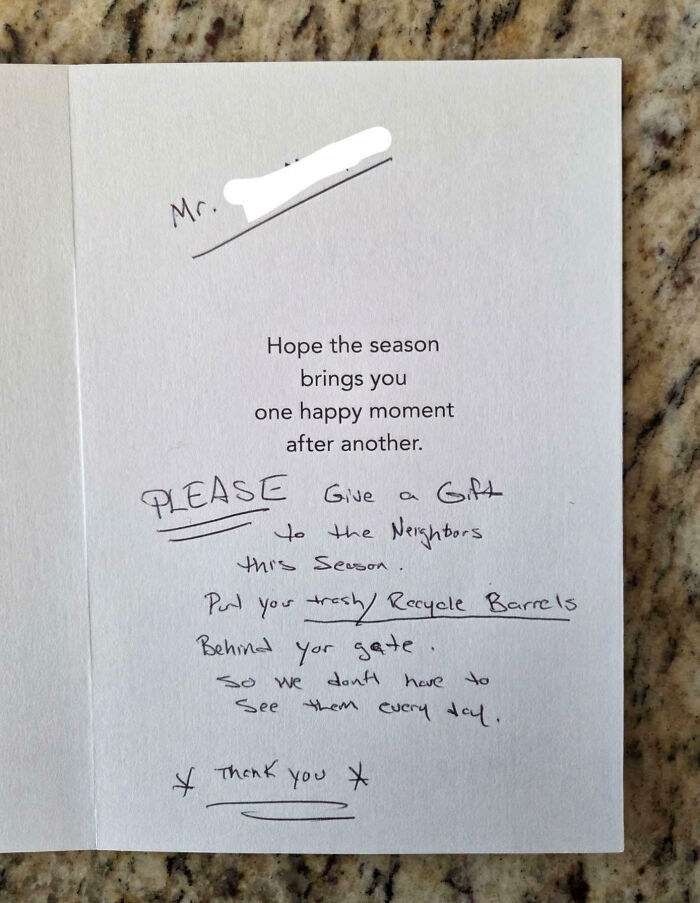 Handwritten note in a holiday card asking neighbors to hide trash and recycle barrels behind their gate.