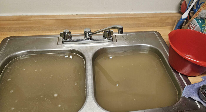 Kitchen sink filled with dirty, murky water representing neighbors that make you want to move to the middle of nowhere.