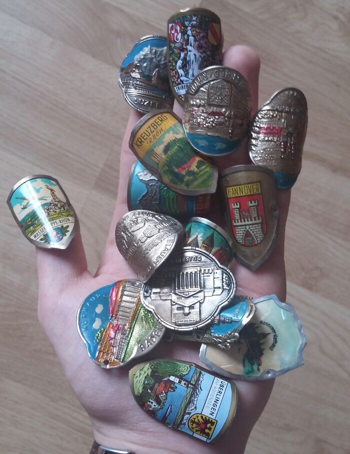 Hand holding various vintage souvenir badges and pins, highlighting internet solving mystery of unidentified objects.