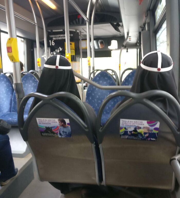 Two passengers in traditional attire seated on a city bus, a scene resembling unidentified objects in public spaces.