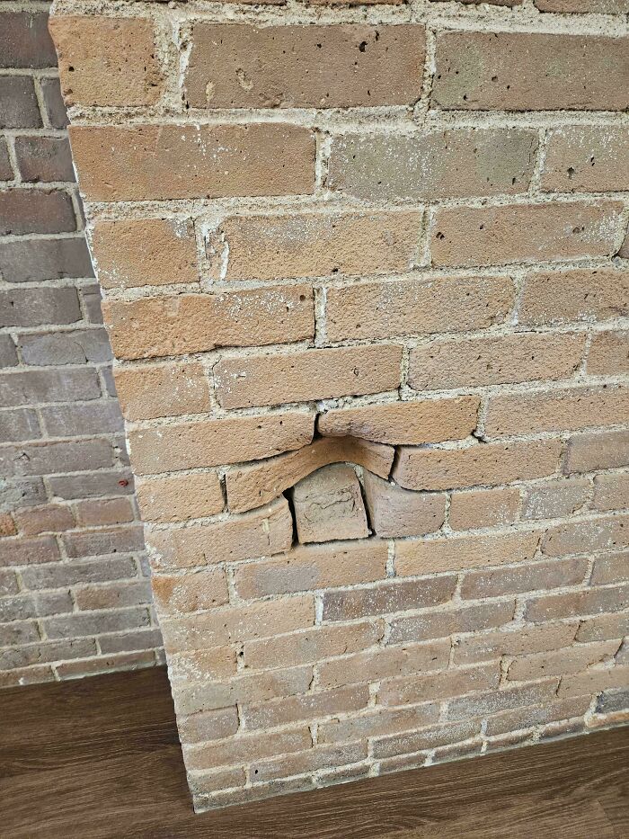 Unexplainable image of a brick wall with an oddly protruding stone broken in an unusual pattern.