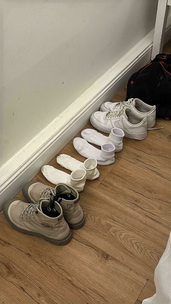 Row of shoes and socks perfectly aligned along the wall creating a weird and unexplainable visual effect.