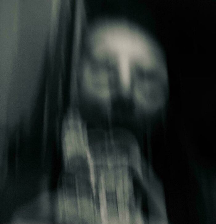 Blurry eerie figure with distorted face in dark surroundings creating a weird and unexplainable image effect