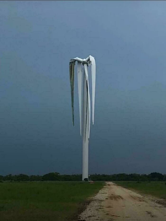 Damaged wind turbine with broken blades standing in a field under a dark, cloudy sky in weird and unexplainable images.