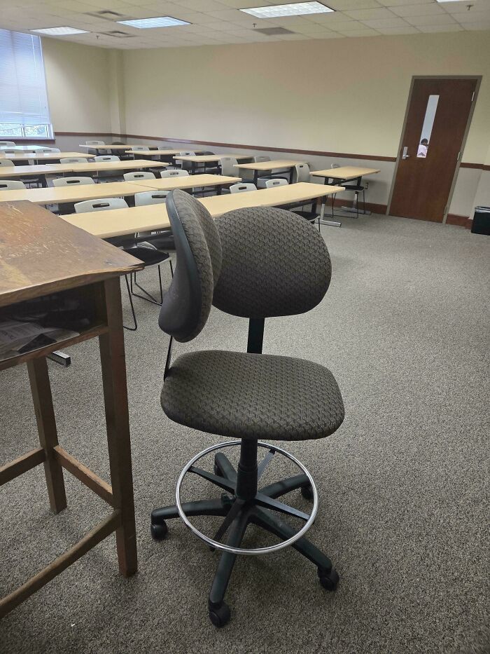Office chair with dual backrests in an empty classroom, a weird and unexplainable image that lingers in your mind.