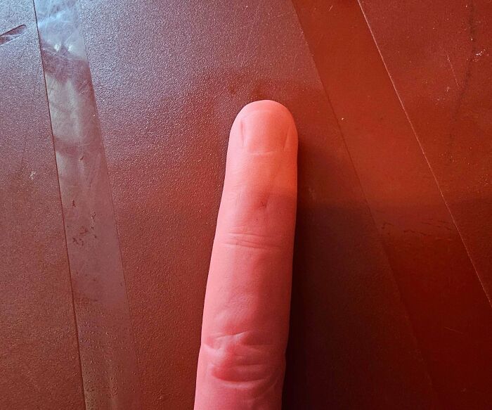 Close-up of a realistic finger-shaped object on a red textured surface, one of the weird and unexplainable images.