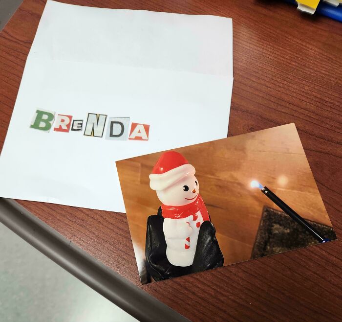 Photo of a ransom note spelling Brenda and a candle-lit snowman figurine, a weird and unexplainable image on a wood table.