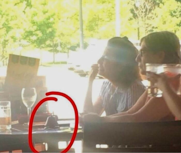 Two women sitting at a restaurant table, one holding a drink, with an object circled highlighting entitled Karens behavior.