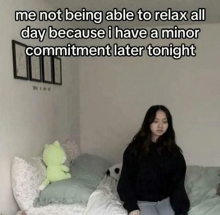 Young woman sitting on bed looking anxious about a minor commitment later, relatable posts and memes about our lives.