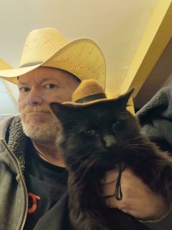 Man and black cat wearing cowboy hats, showcasing dads and pets bonding unexpectedly and lovingly.