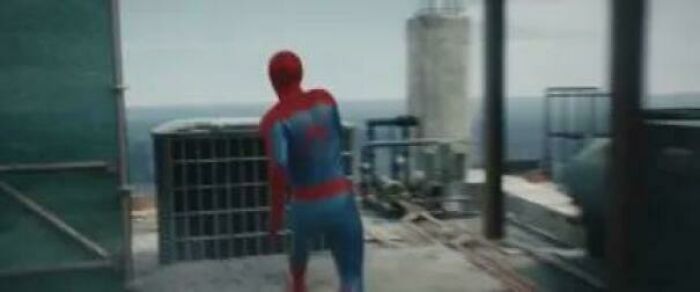 Spider-Man in his suit on a rooftop looking out at the ocean, a hilarious example of nonsensical movie details.