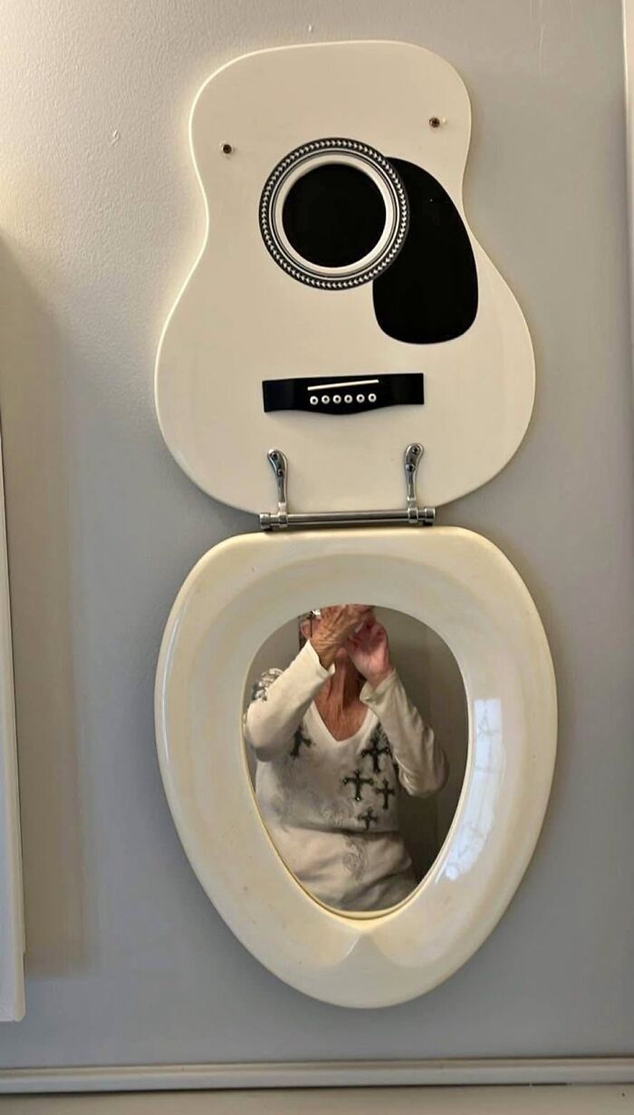 Toilet seat designed like a guitar with a person reflected in the mirror inside the seat, an unhinged Facebook Marketplace pic.