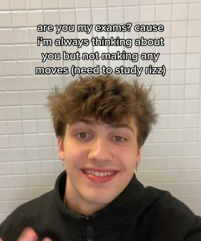 Young man smiling in front of a tiled wall with a meme about exams and needing memes to function properly.