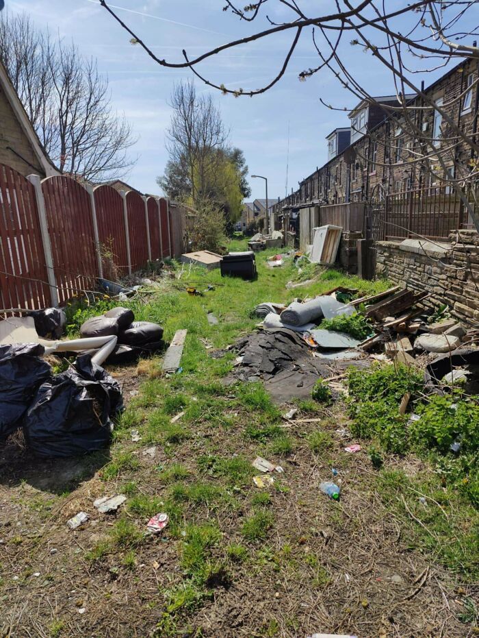Urban hell alley filled with trash and debris between houses and fences