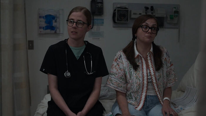 Two women sitting in a dimly lit room, highlighting guest stars in The Pitt Season 2 Episode 11 setting.