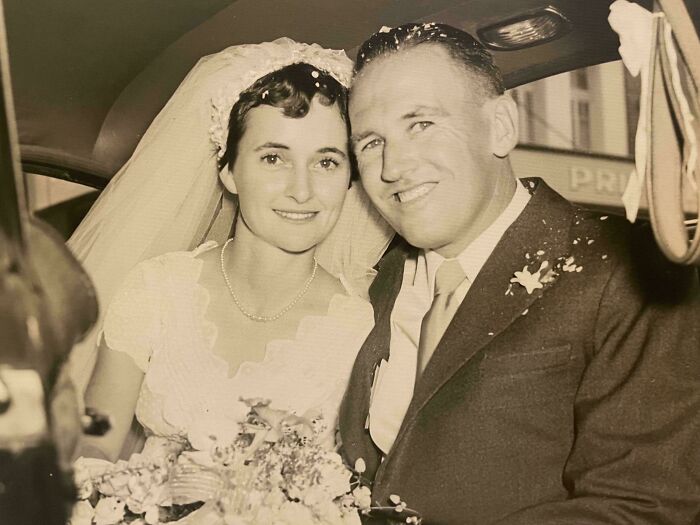 A candid old photo of a newly married couple smiling in a car on their wedding day, revealing what the world looked like generations ago.