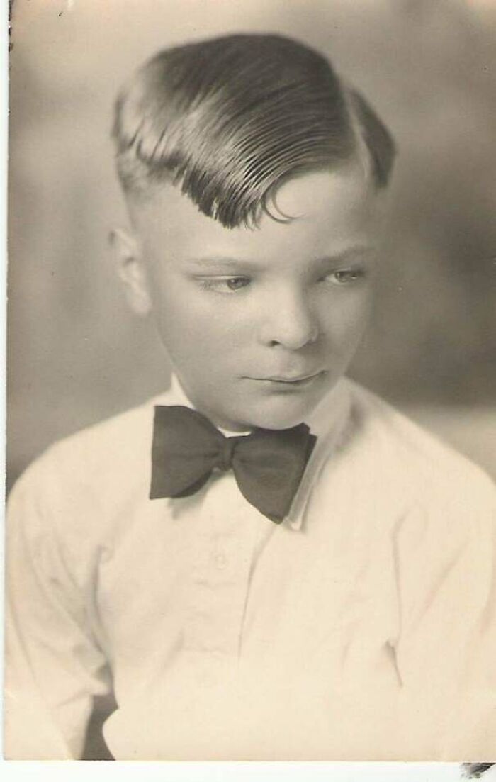 A candid old photo of a young boy wearing a bow tie with a neatly combed hairstyle, revealing what the world looked like generations ago.