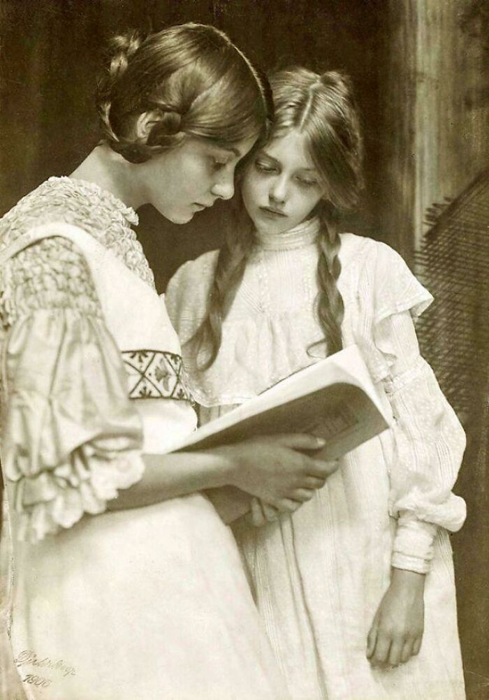 A candid old photo showing two young girls looking at a book together, revealing what the world looked like generations ago.