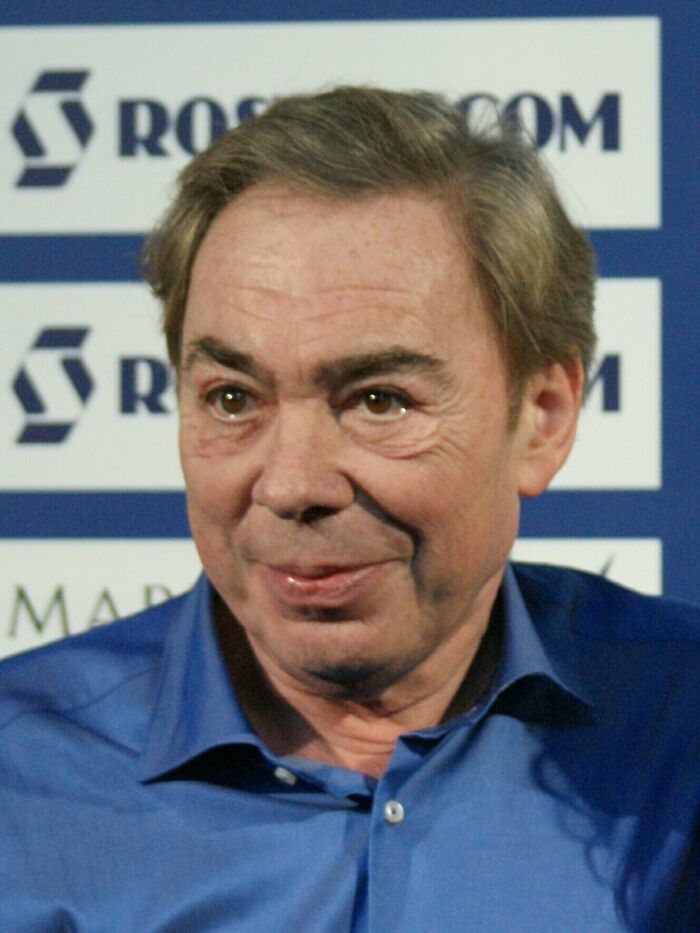 Andrew Lloyd Webber at an event, wearing a blue shirt, showcasing his influence in musical theater and career highlights.