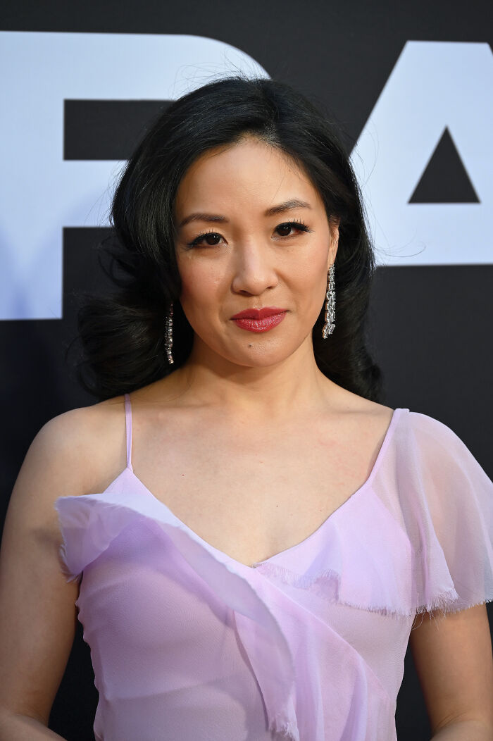 Constance Wu wearing light purple dress and dangling earrings at a formal event, highlighting her bio and career.
