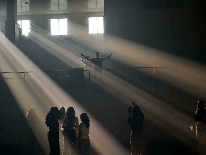 Silhouettes of people in a dark room under dramatic light beams, in Accidental Renaissance style