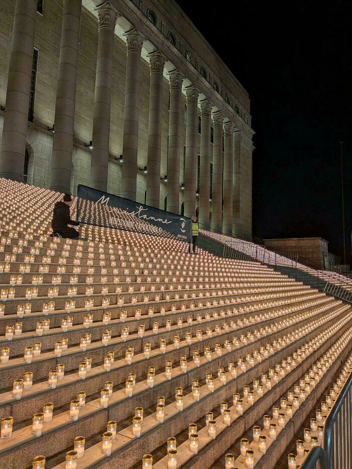 A grand building staircase adorned with hundreds of lit candles, illustrating a large-scale event related to consumerism.