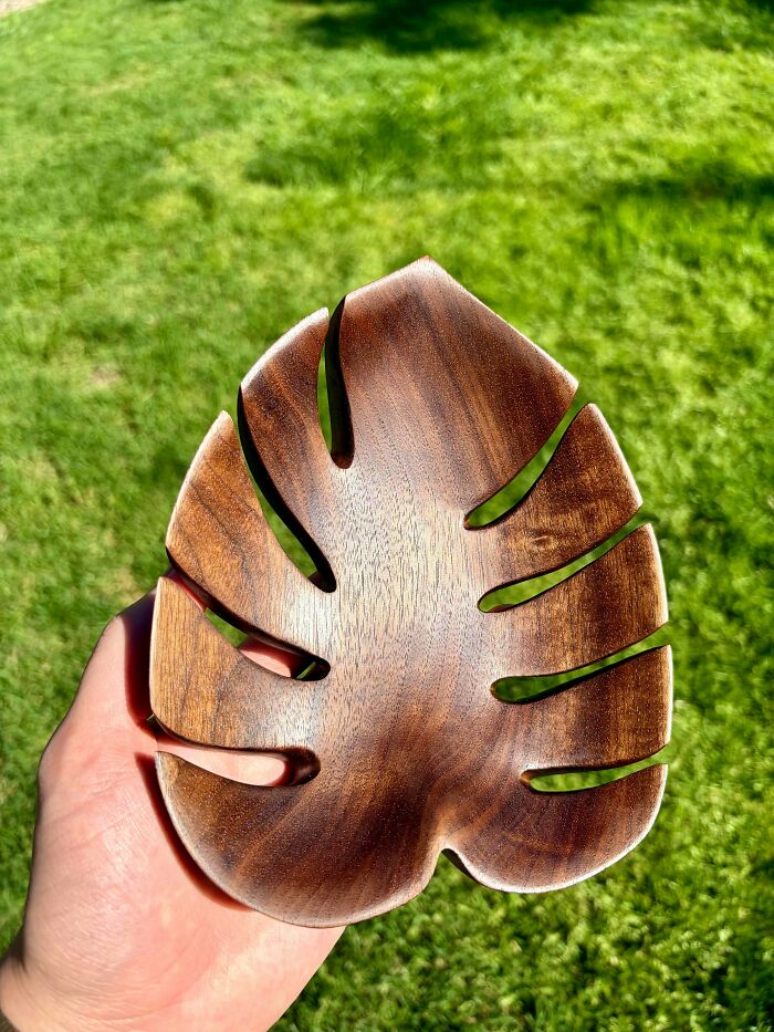 Hand holding a smooth wooden leaf-shaped diy project, showcasing a creative diy win in natural outdoor light.
